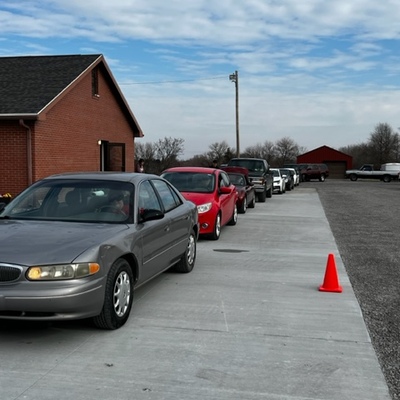Commodities - Cars lined up for items to be placed in vehicles after people have checked in.