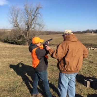 A board member helping a Youth Pheasant Hunter how to cradle a gun correctly.